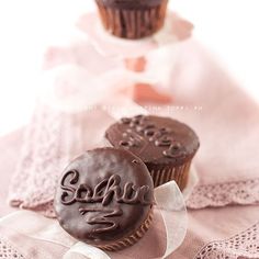 two chocolate cupcakes sitting on top of a white table cloth next to each other