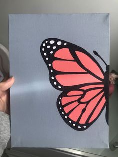 a person holding up a painting with a butterfly on it's back and pink wings