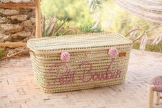 a large woven basket with the word love written on it and pink pom poms