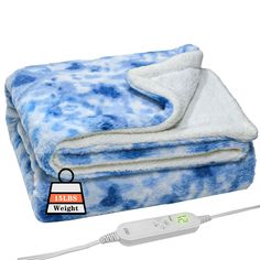 a blue and white blanket sitting on top of a bed next to a remote control