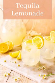 two glasses filled with lemonade sitting on top of a wooden table next to sliced lemons