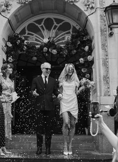 a bride and groom standing in front of a doorway surrounded by confetti