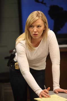 a woman is writing on a piece of paper while standing in front of a desk