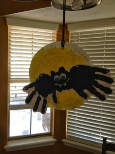 a handprinted bird hanging from the ceiling in front of a window with blinds