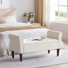 a white bed sitting next to a window in a bedroom