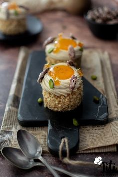 some kind of food that is on top of a black plate with spoons next to it