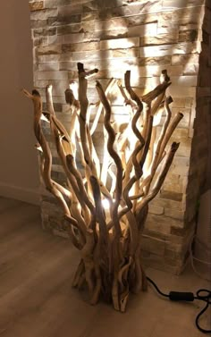 a lamp made out of driftwood is lit up in front of a brick wall