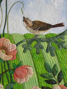 a bird sitting on top of a patchwork piece of fabric with flowers and leaves