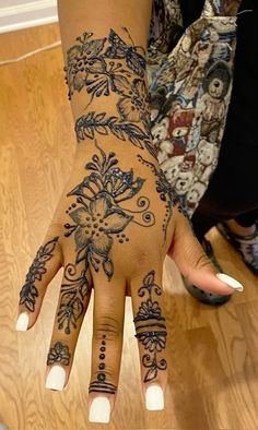 a woman's hand with hennap and flowers on her left arm, showing the