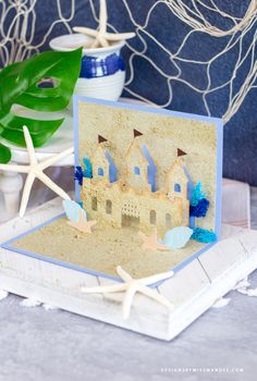 a handmade card with sand castle and starfish on the table next to it