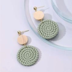 two circular earrings with wooden discs on them, one is green and the other is beige