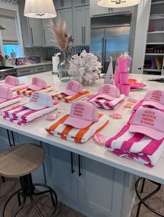 pink and orange hats sitting on top of a kitchen counter next to two stools