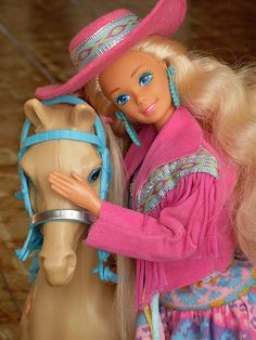 a barbie doll is petting a horse on the head while wearing a pink hat