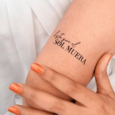 two hands with orange manicures holding onto each other's arm and the word tattoo on them