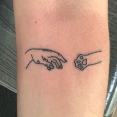 two hands touching each other on the left side of the arm, one with a skull in it