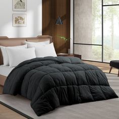 a black comforter on a bed in a room with wood paneling and windows