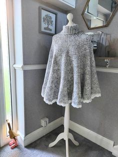 a white mannequin with a gray sweater on it in front of a mirror