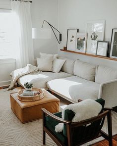 a living room with white couches and pictures on the wall above them, along with a coffee table