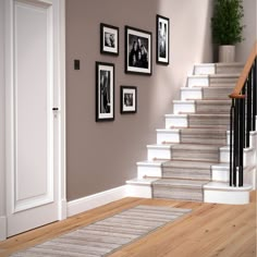 a stair case with pictures on the wall and carpeted floor in front of it