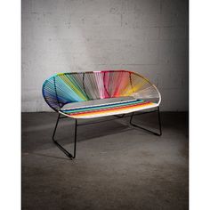 a multicolored bench sitting on top of a cement floor next to a wall