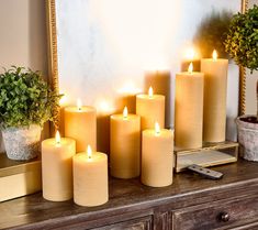 a group of lit candles sitting on top of a wooden table next to a mirror