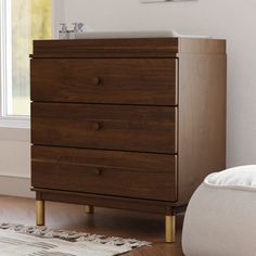 a wooden dresser sitting next to a window in a room with a rug on the floor