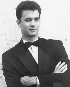 a black and white photo of a man in a tuxedo with his arms crossed