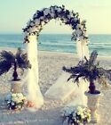 an arch decorated with flowers and greenery on the beach