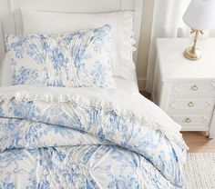 a blue and white comforter on a bed in a room with two nightstands