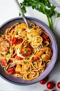 pasta with shrimp, tomatoes and parsley in a blue bowl on a white table