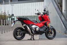 a red and black motorcycle parked in front of a building