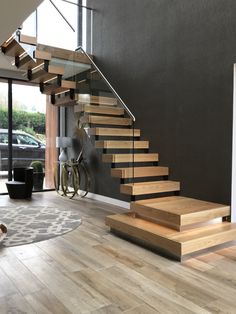 there is a bike parked next to the stairs in this living room with wood flooring