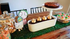 a table topped with cakes and desserts on top of green moss covered trays