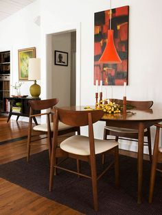 a dining room table with four chairs and a painting hanging on the wall behind it