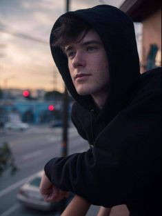 a young man in a hoodie looking at the camera