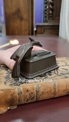 a person's hand resting on top of a book with a bird figurine