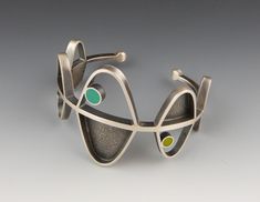 The design for the Helix Cuff bracelet was inspired by the ordered symmetry of DNA strands. Hand fabricated from sterling silver with an oxidized and brushed finish. Inlays of eco-friendly, soy-based resin. The resin is hand-tinted with non-toxic pigments. Fits 6” to 6.5” wrist, other sizes may be custom made. 1.625” x