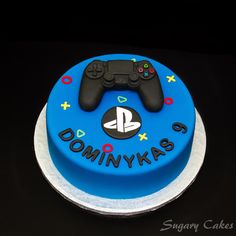 a blue cake with a video game controller on it's top and the words dommy kas written in black