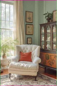 a white chair sitting in front of a window next to a dresser and potted plant