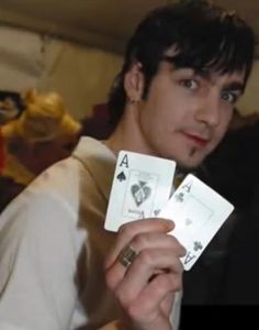 a young man holding two playing cards in his hands