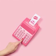 a pink toy calculator with a note sticking out of it