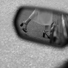 a woman's reflection in the side view mirror of a car with her shoes on