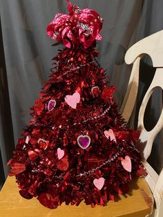 a red tinsel christmas tree sitting on top of a wooden chair