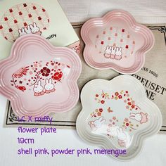 three pink plates with designs on them sitting next to each other and the words flower plate