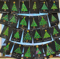 christmas tree cards are hanging on the wall in front of a bulletin board with writing