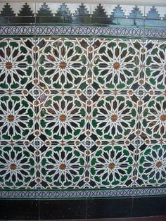 an intricately designed tile in the middle of a room with green and white tiles