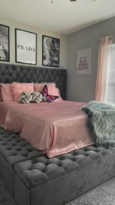 a bed with pink sheets and pillows in a bedroom next to two pictures on the wall