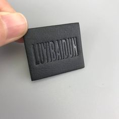 a hand holding a black leather label that says lubraton on the front and side