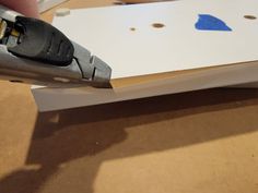 a pair of pliers cutting paper on top of a piece of cardboard with holes in it