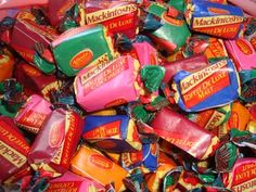 a pile of assorted candy bars sitting in a pink container on top of a table